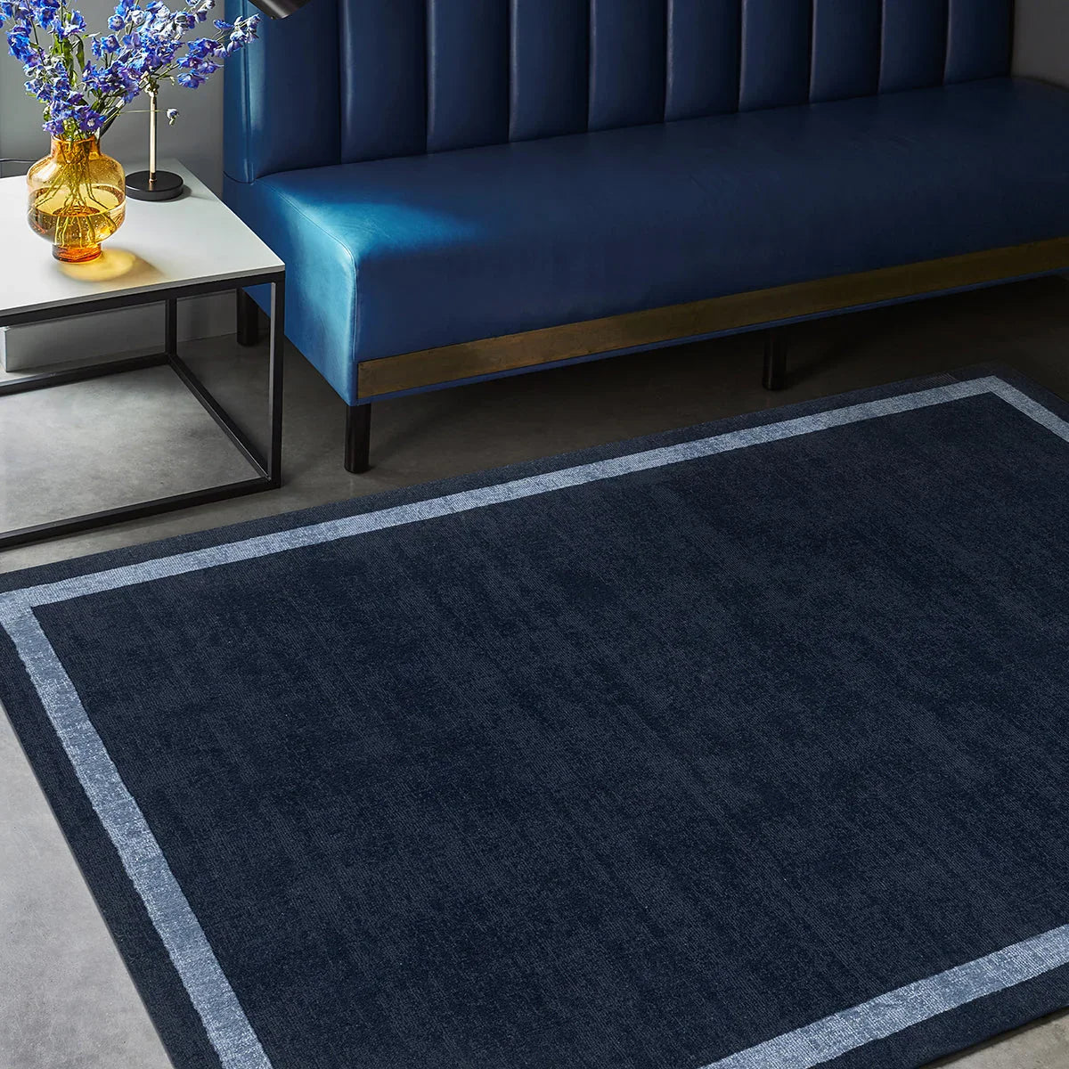 Asiatic Albi Navy Designer Rug featuring solid navy field with powder-blue border on grey floor, power-loomed wool