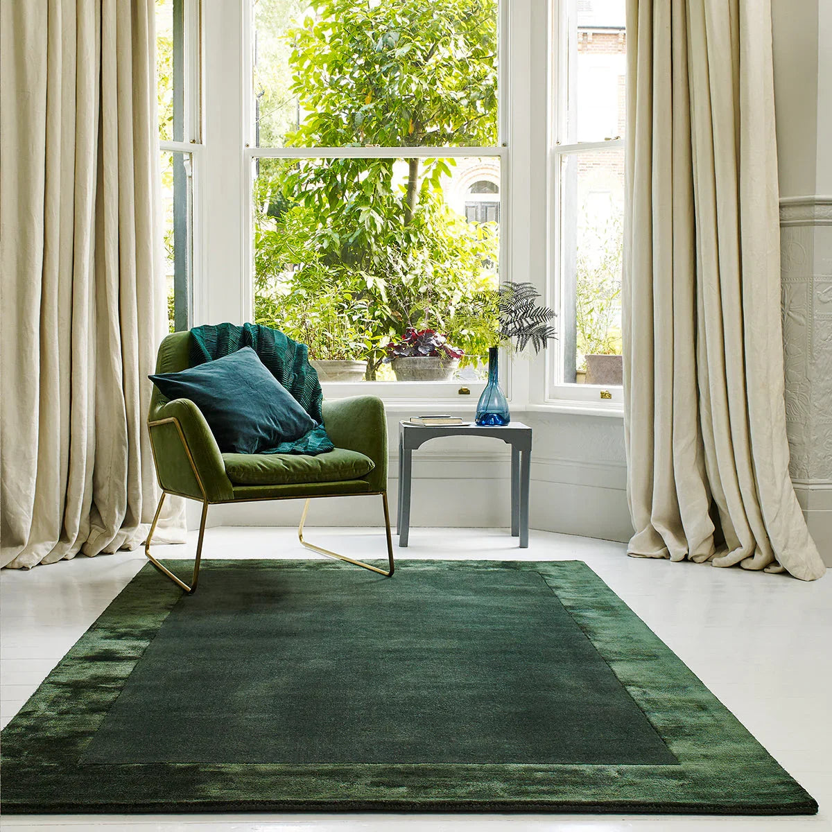 Asiatic Ascot Green Designer Rug featuring deep forest green field with olive and emerald border on white floor, hand-tufted wool