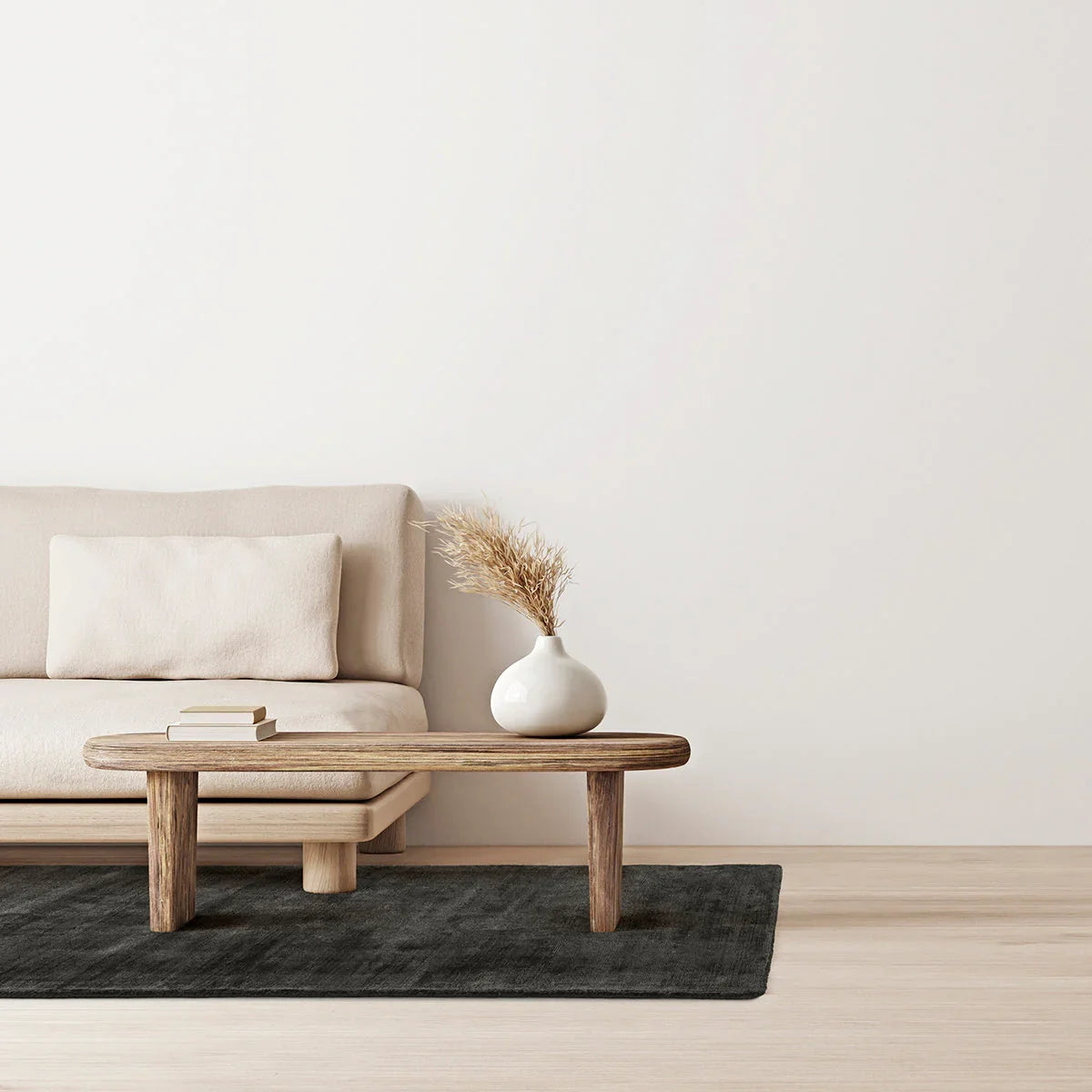 Asiatic Blade Charcoal Runner rug in solid charcoal on light-wood floor beneath beige sofa and white vase.