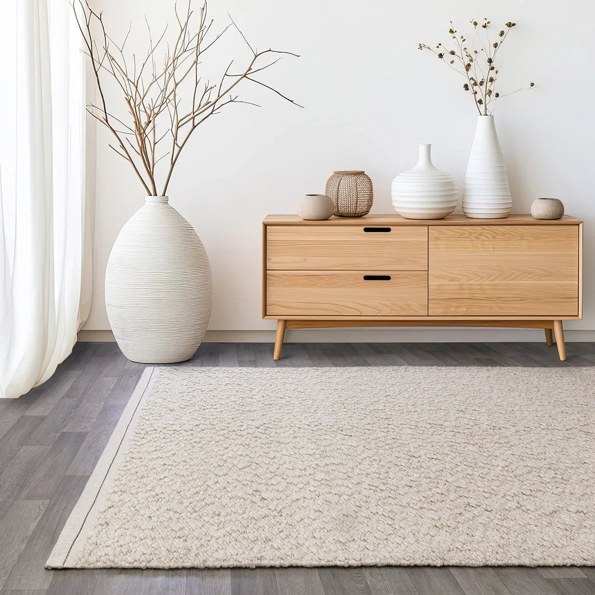 Wooden sideboard with decorative items in a room with a rug and curtains.