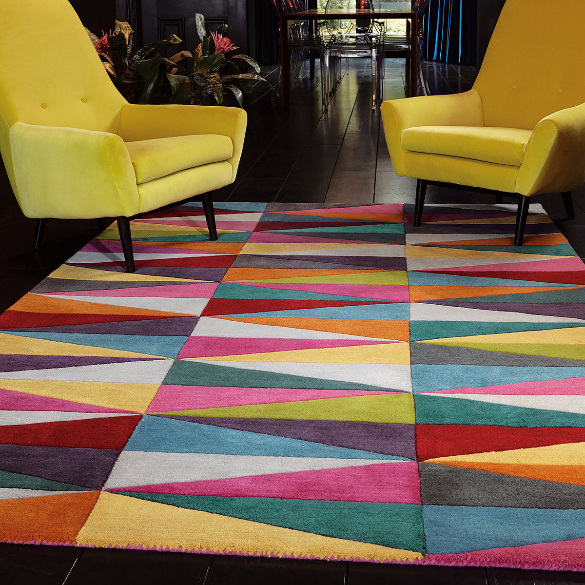 Colorful geometric-patterned rug in a room with yellow chairs.