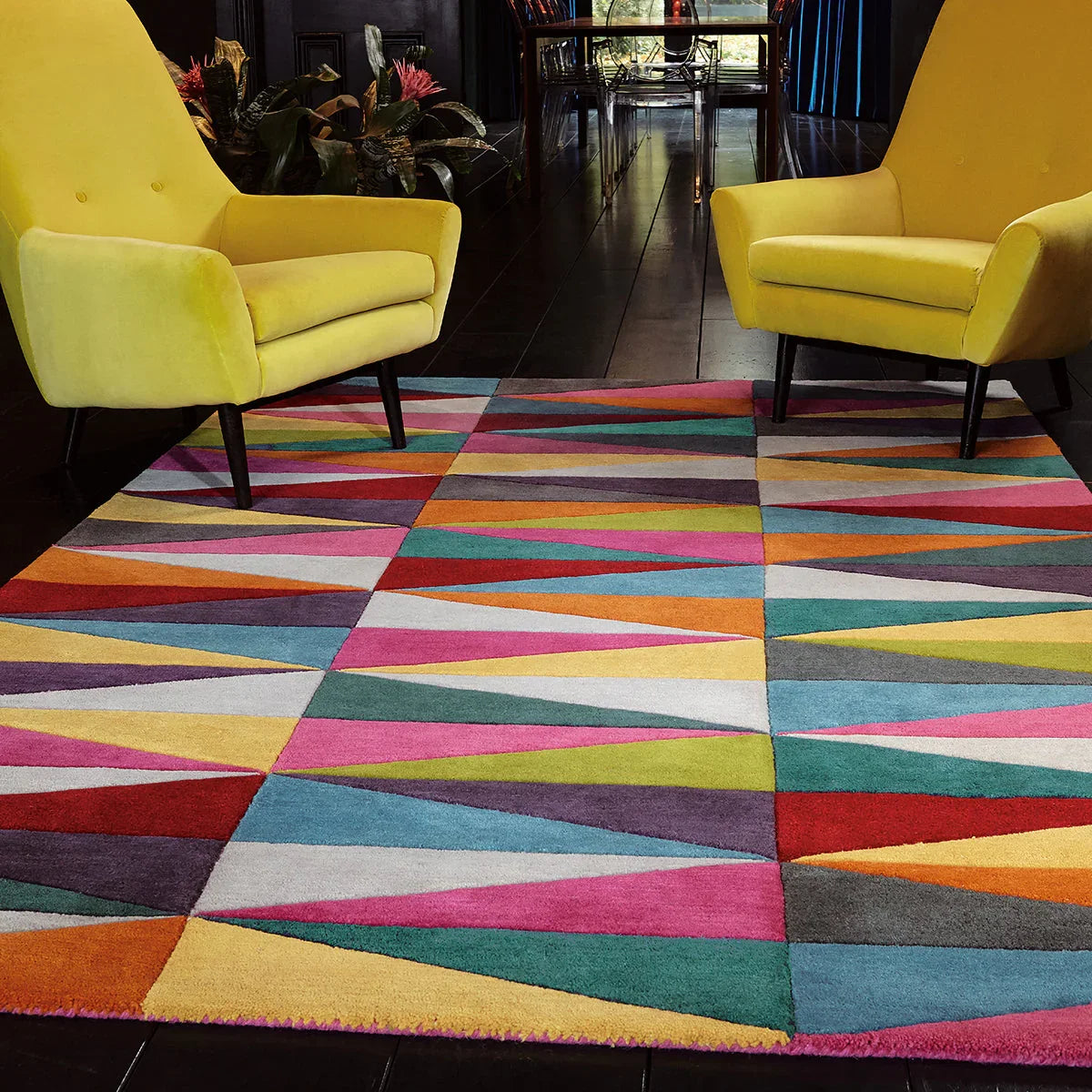Colorful geometric-patterned rug in a room with yellow chairs.