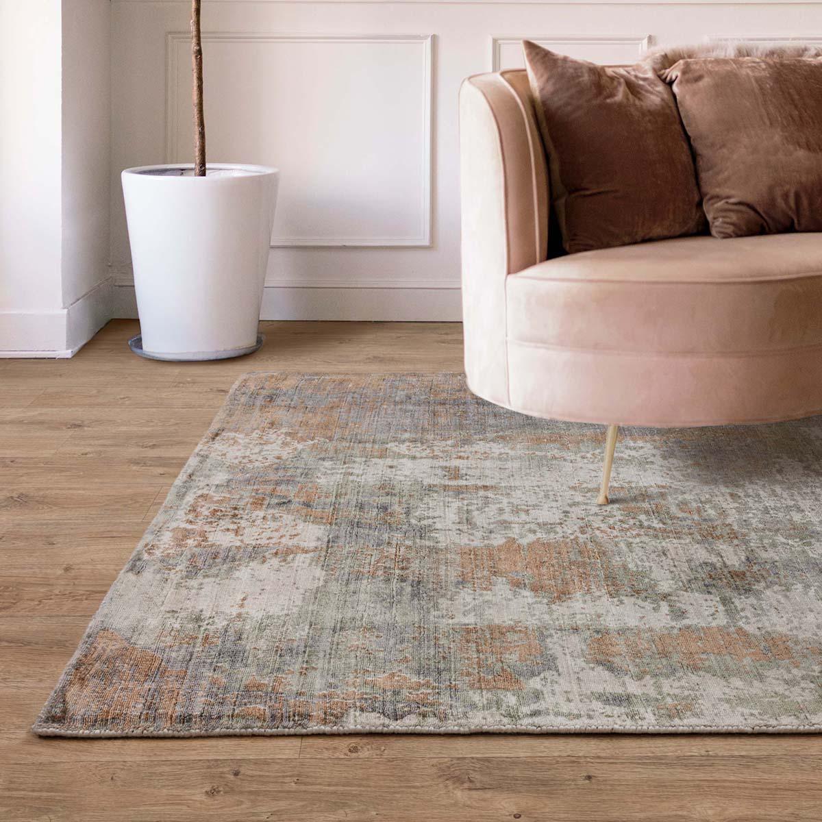 Living room with a patterned rug, beige sofa, and white wall.