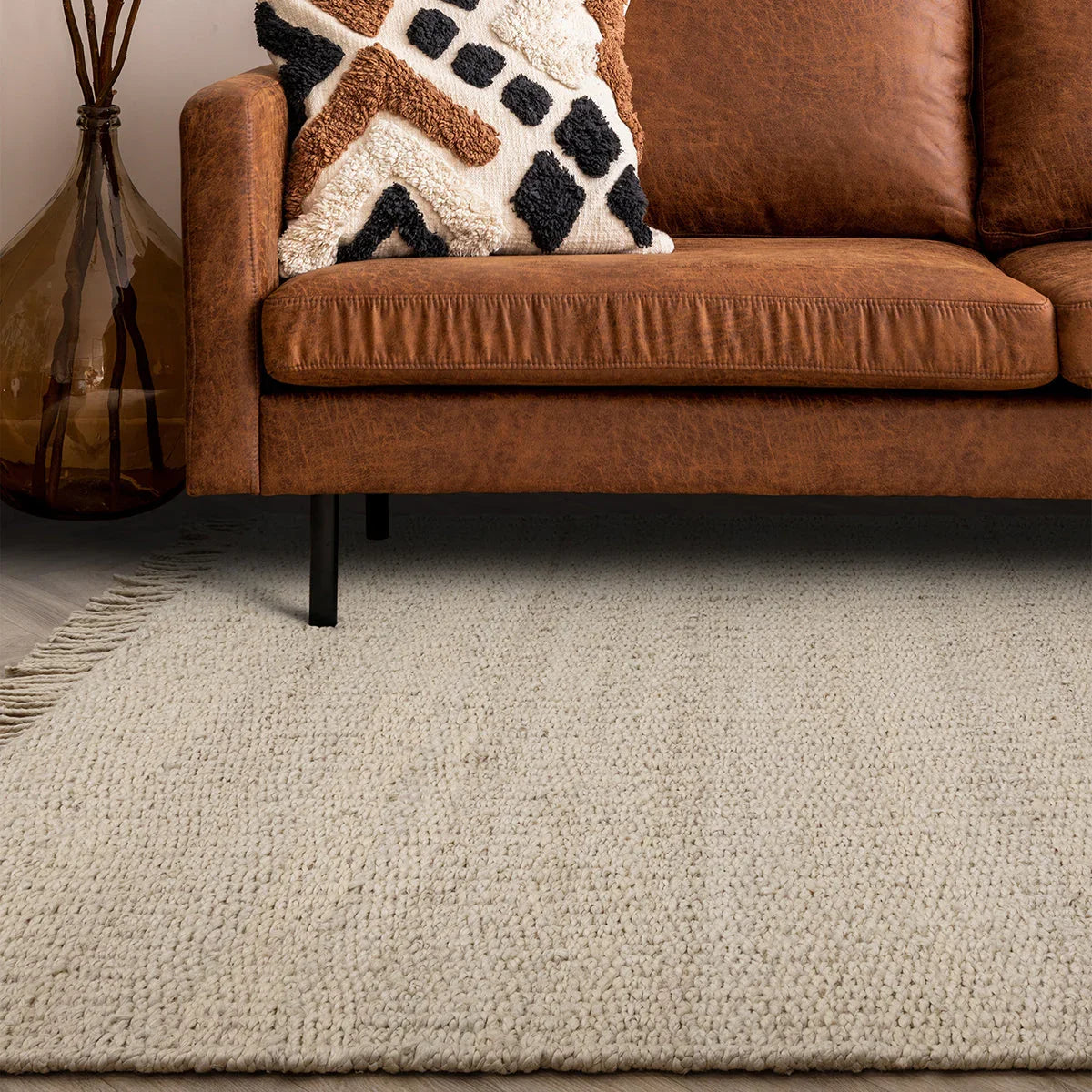 Brown sofa with a patterned pillow on a textured gray rug