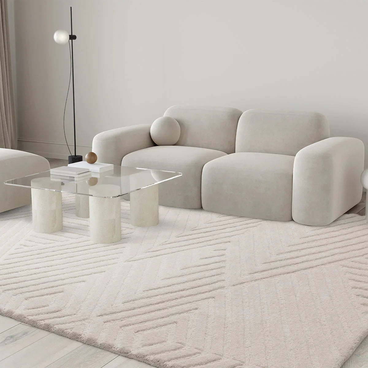 Modern living room with a beige sofa, glass coffee table, and decorative rug.