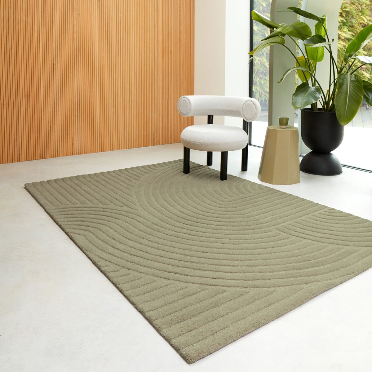 Green textured rug in a modern room with a white chair and plant.