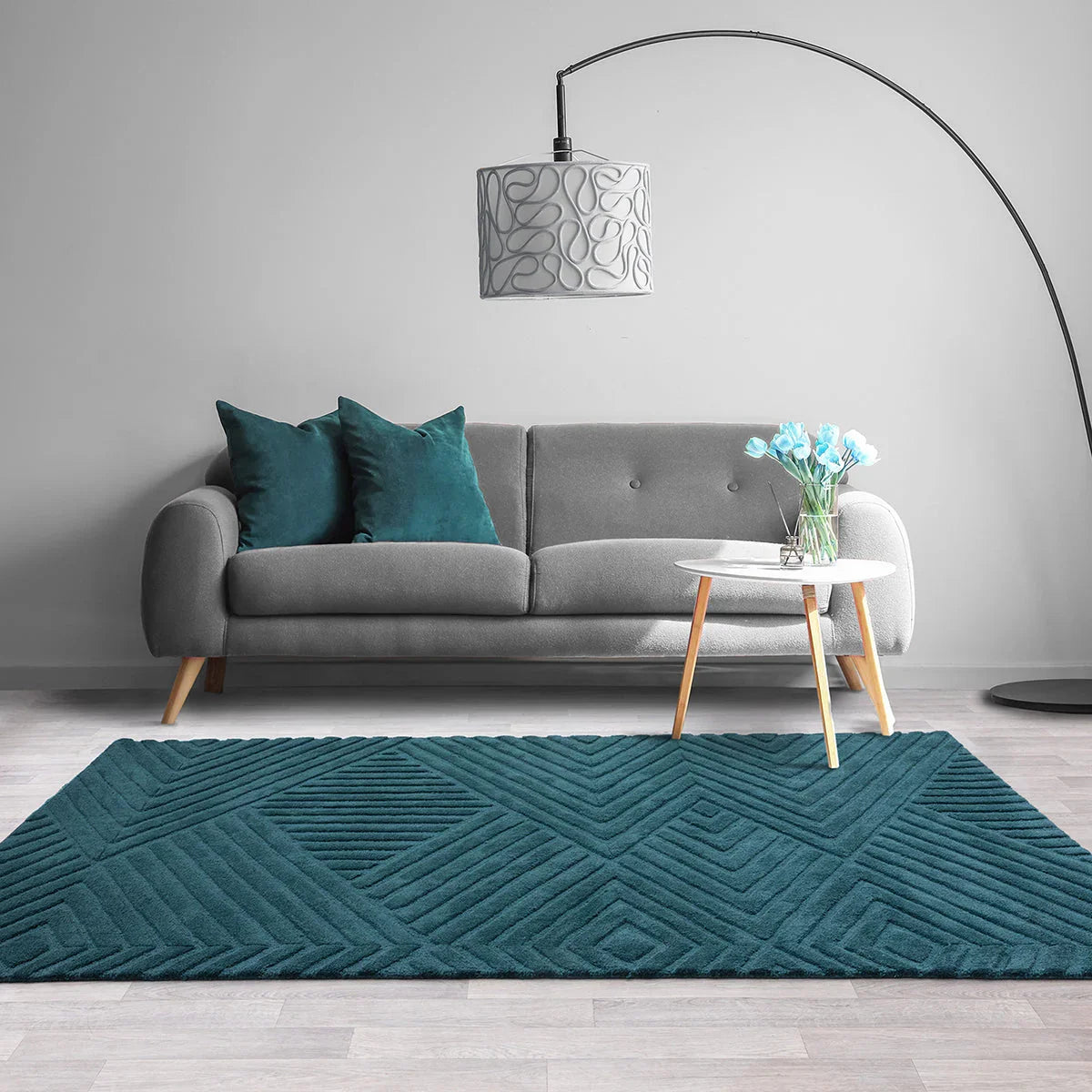 Living room with a gray sofa, teal rug, and decorative lamp.