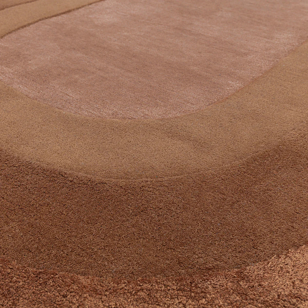 Asiatic Halo Clay Designer Oval Rug featuring halo pattern in clay, terracotta and dusty pink on warm tan background, hand-tufted wool
