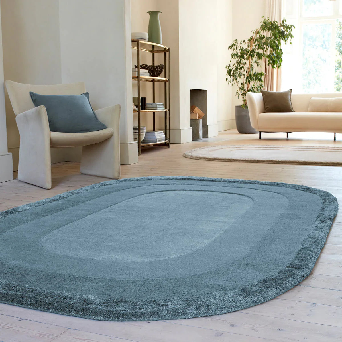 Blue oval rug in a living room with a sofa and chair.