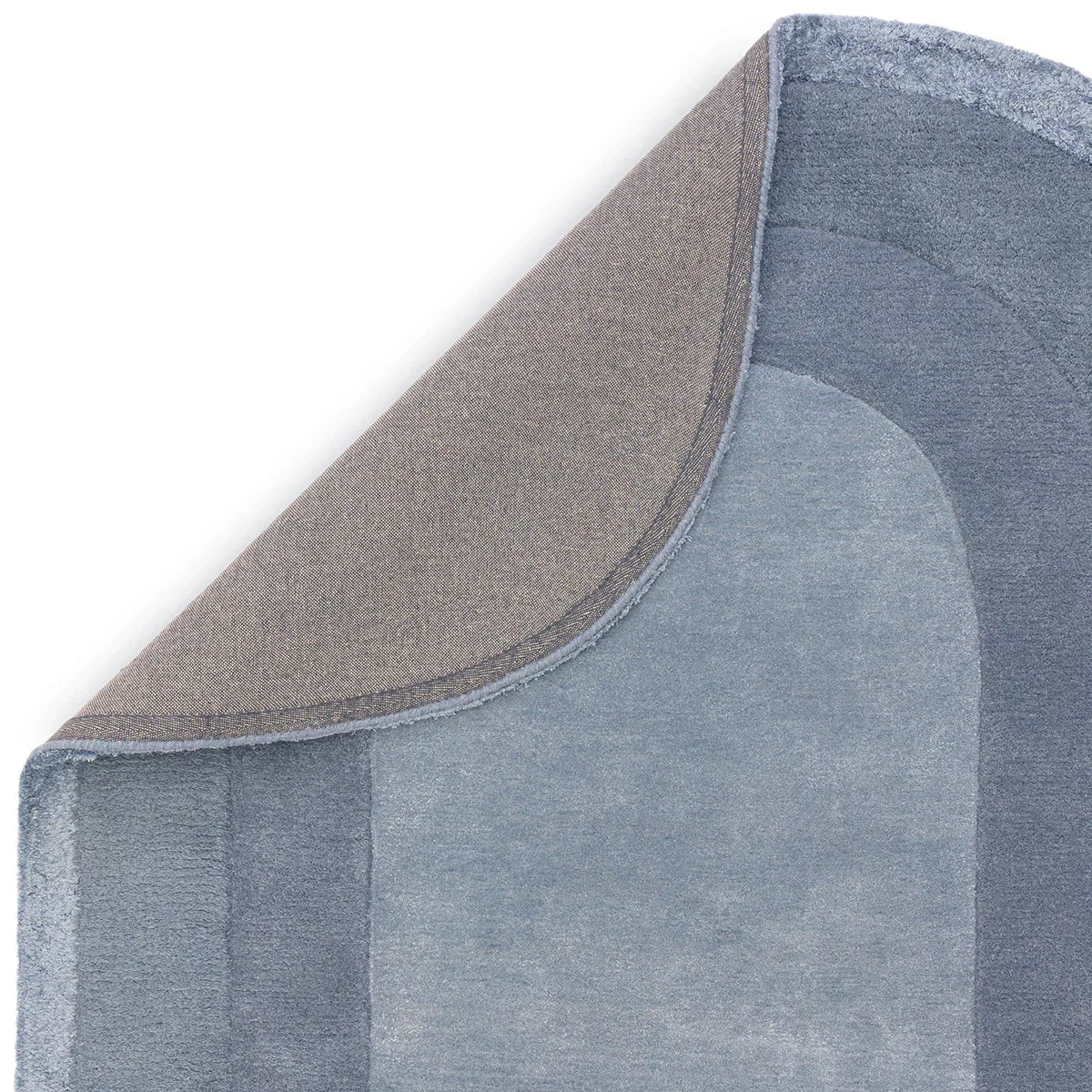 Asiatic Halo Denim oval rug featuring patchwork curved panels in denim blue, steel blue and navy on white background, hand-tufted wool