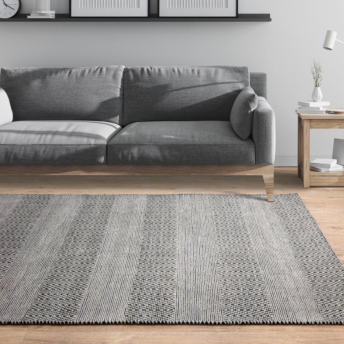 Gray sofa in a living room with a patterned gray rug on the floor.