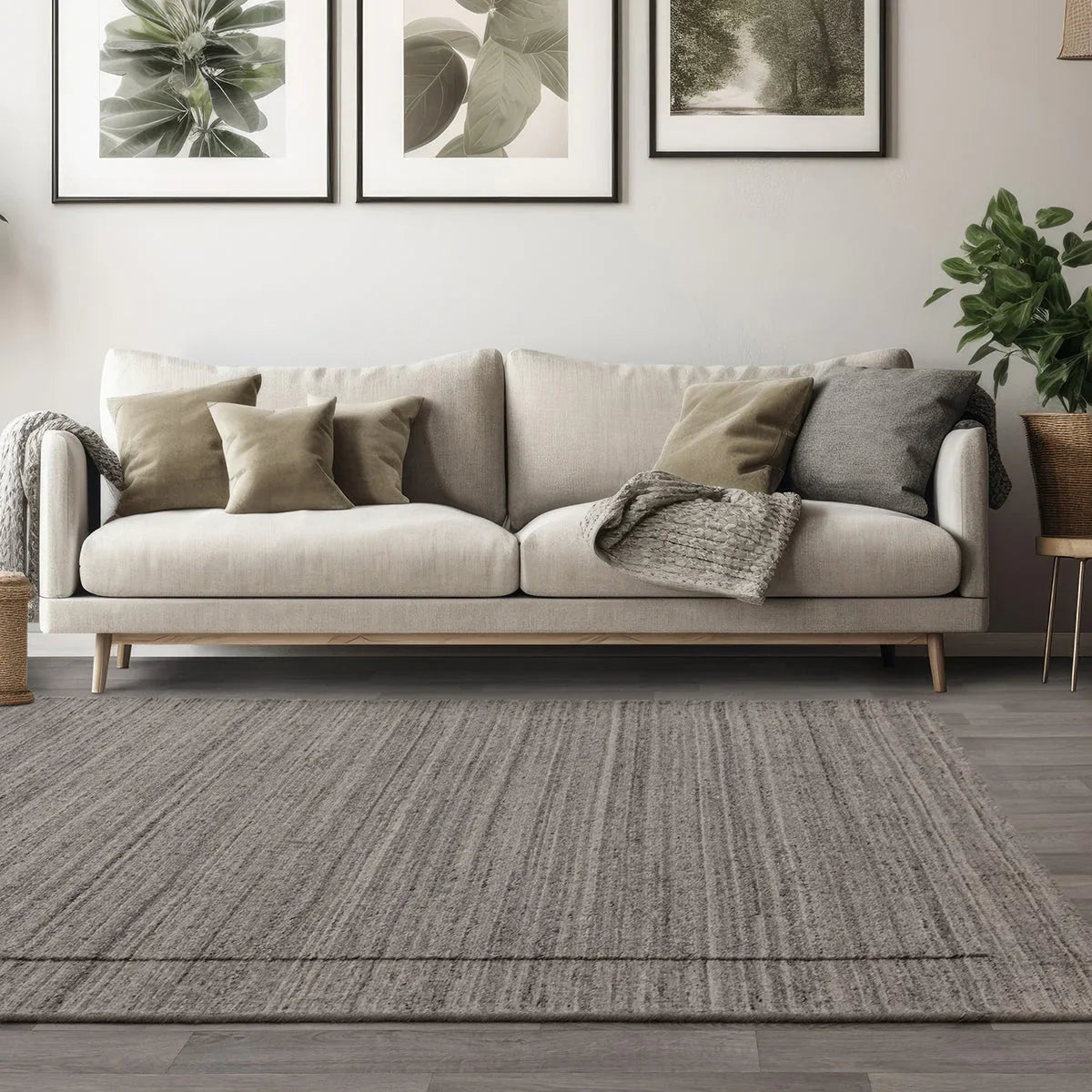 Beige sofa with decorative pillows in a living room setting with framed artwork on the wall.