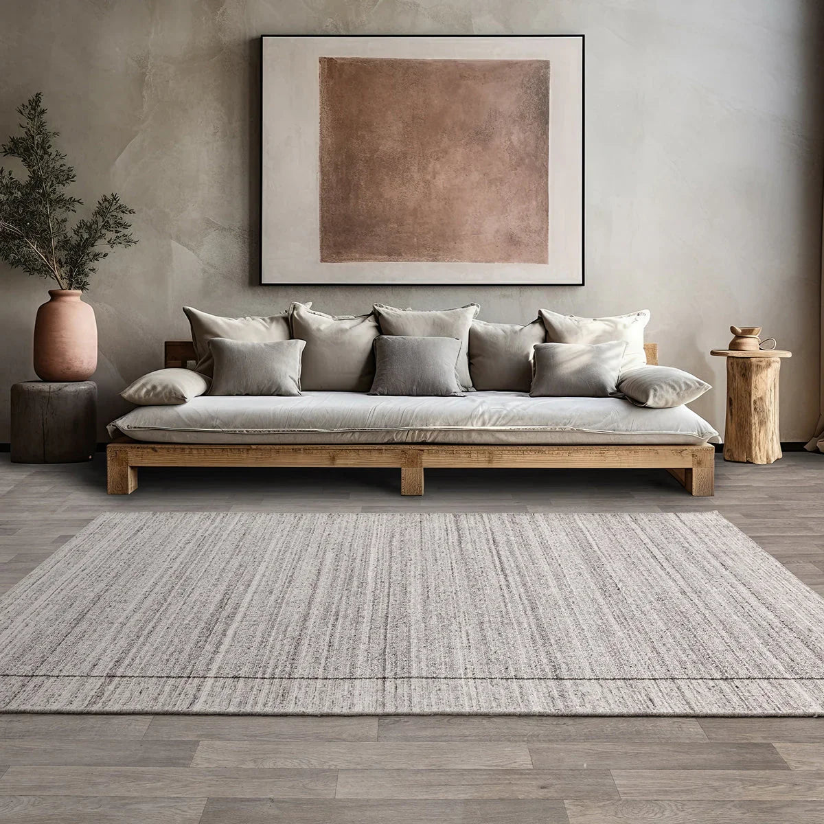 Living room with a wooden sofa, cushions, and a framed abstract painting on a textured wall.