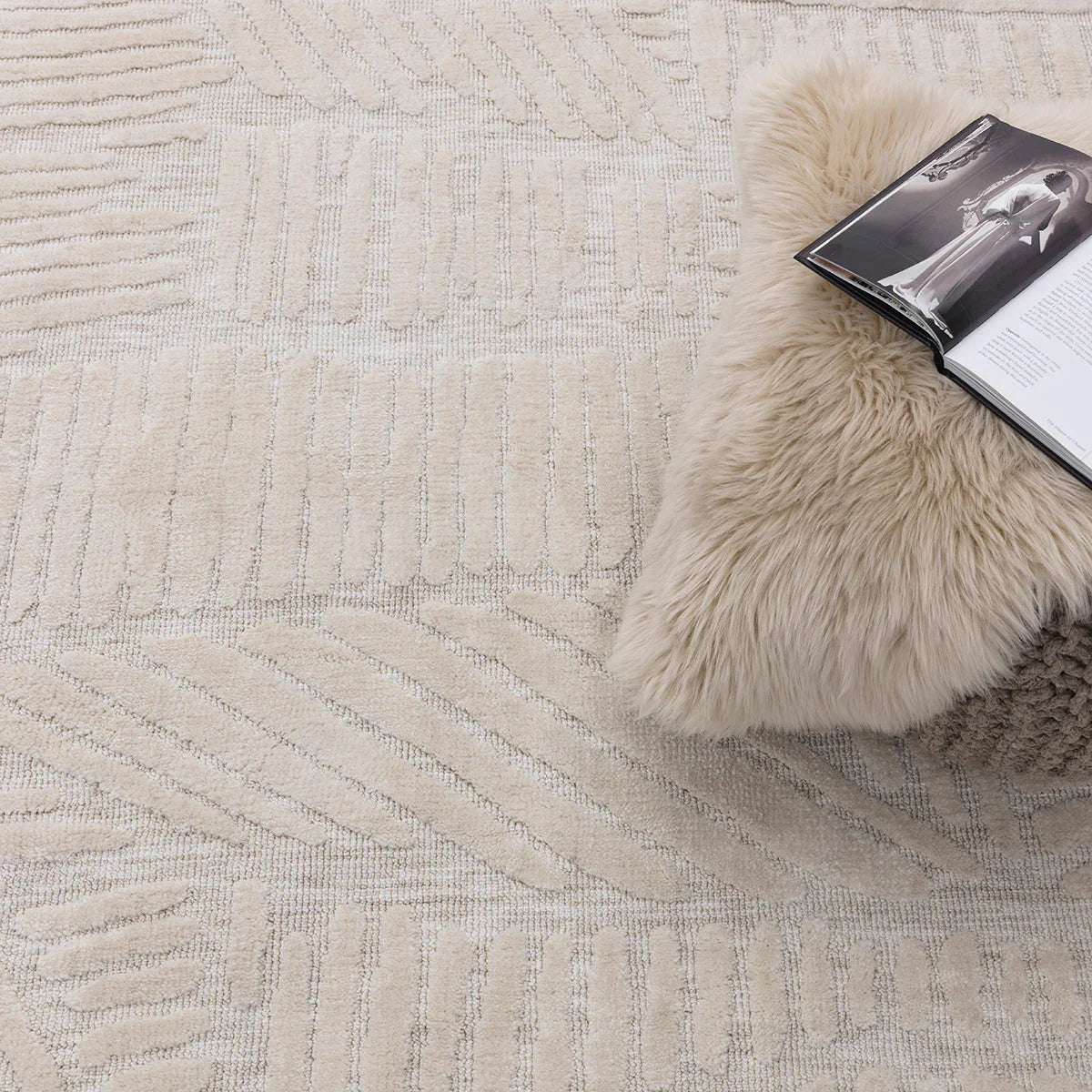 Textured beige rug with a fur throw and book on top