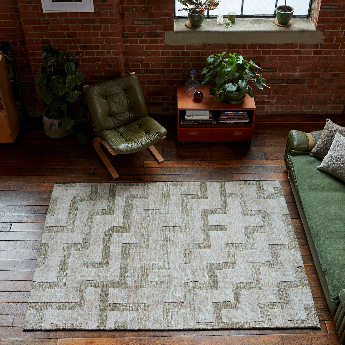 Living room with a geometric patterned rug, green chair, and sofa.