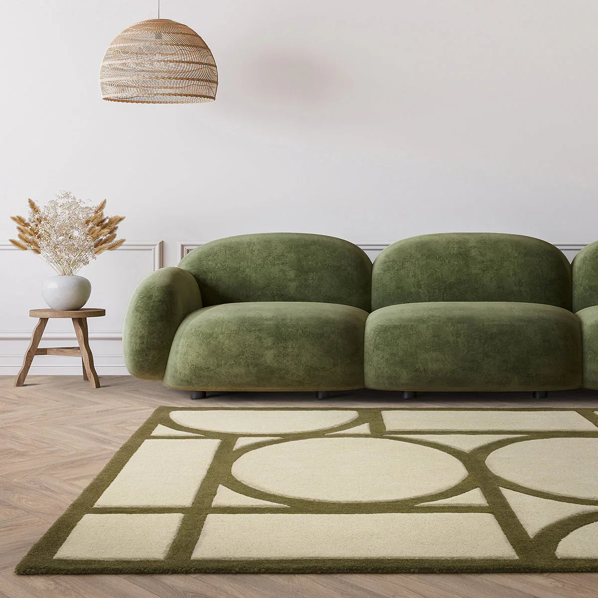 Green sofa in a room with a geometric patterned rug and decorative lamp.