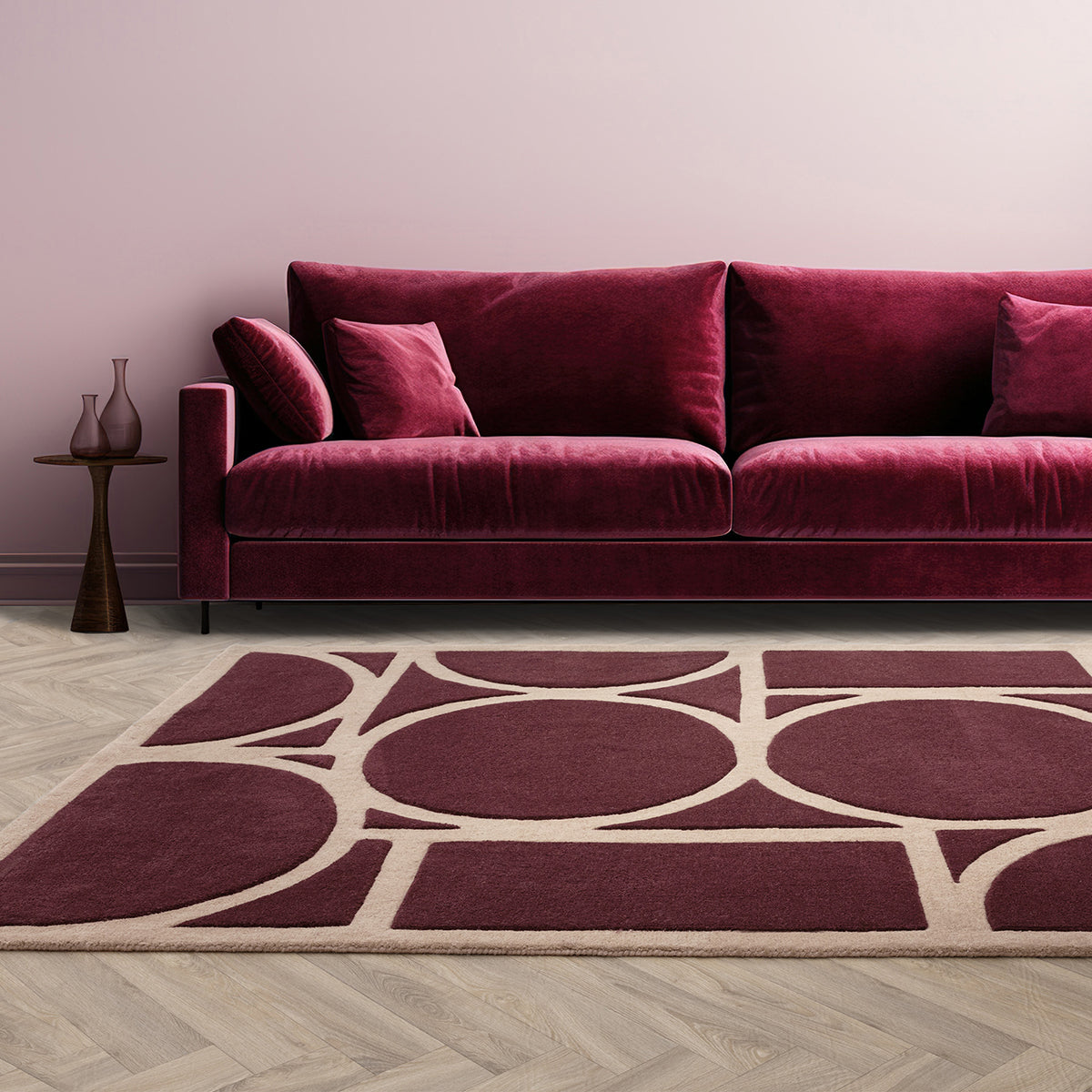 Maroon sofa in a room with a geometric patterned rug on the floor.