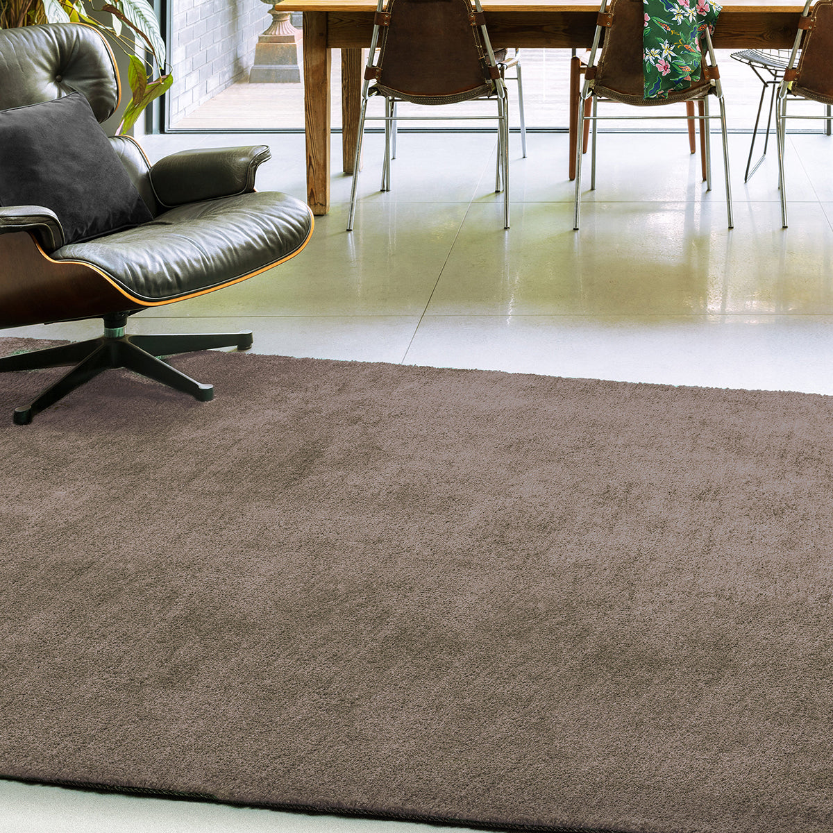 Brown rug on a white floor with a chair and table in the background