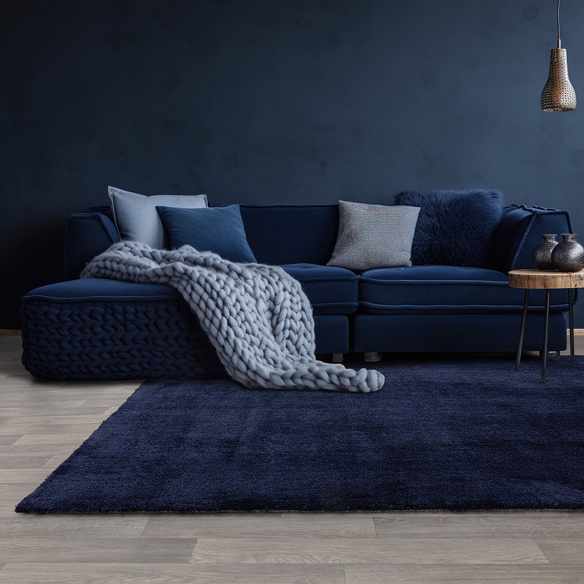 Blue sectional sofa with cushions and a blanket in a dark room