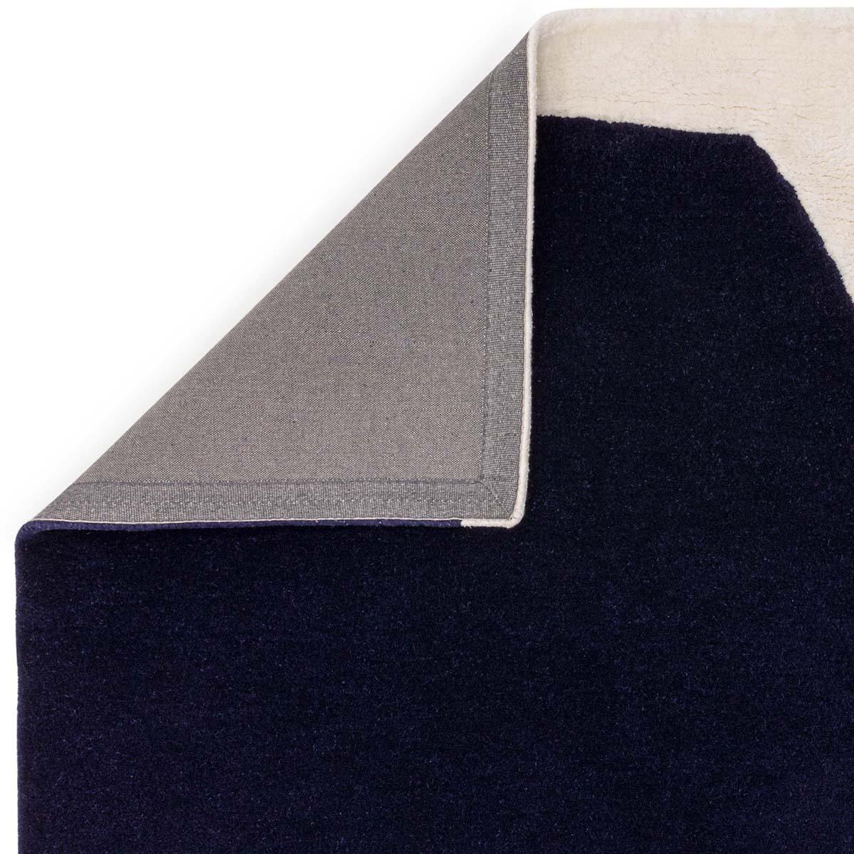 Asiatic Matrix Signature Indigo Rug featuring solid indigo navy field with grey backing on cream edge, hand-tufted wool