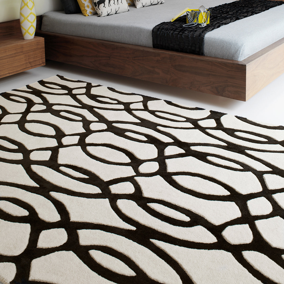 Patterned rug on a floor with a bed in the background