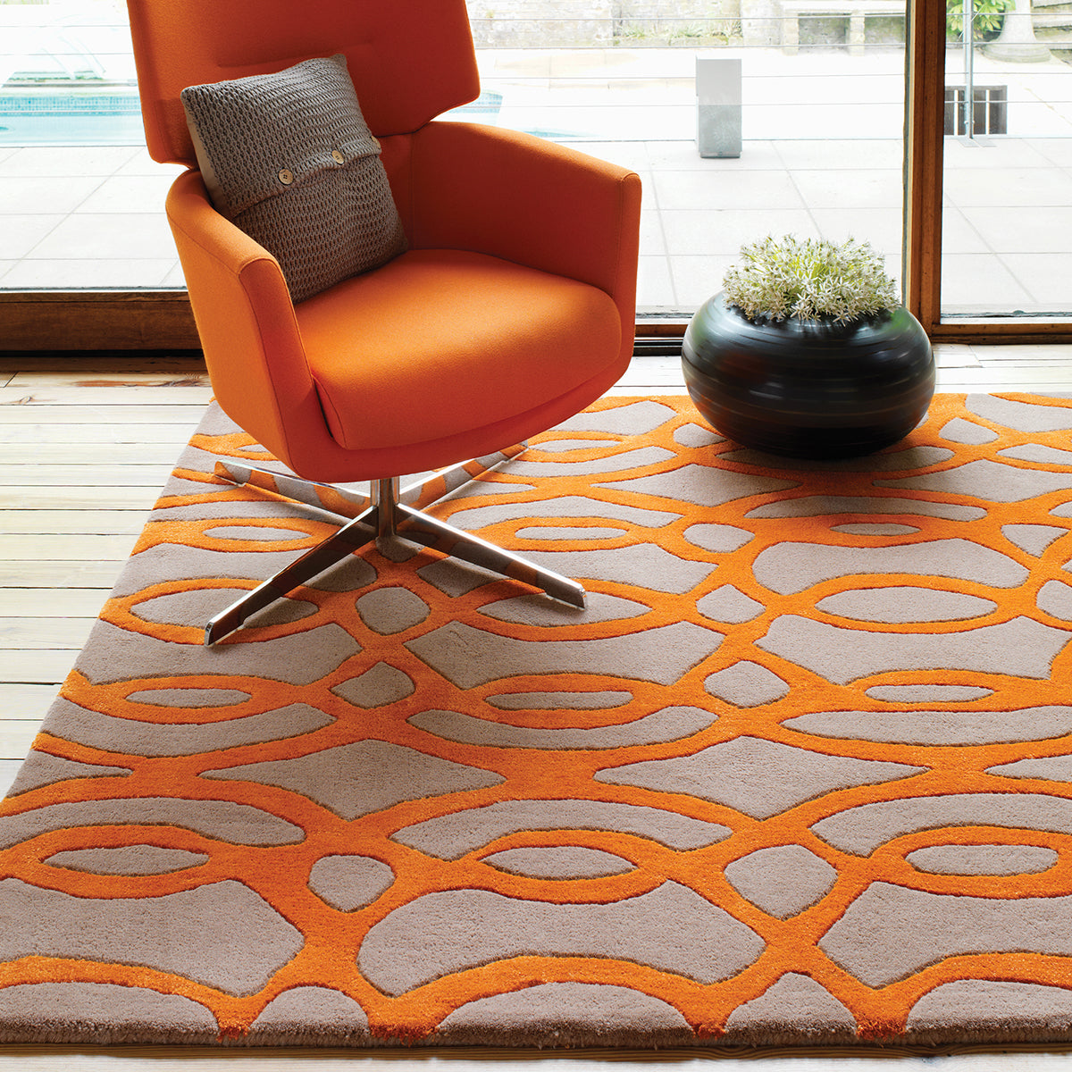 Orange armchair on a patterned rug with a plant in the background