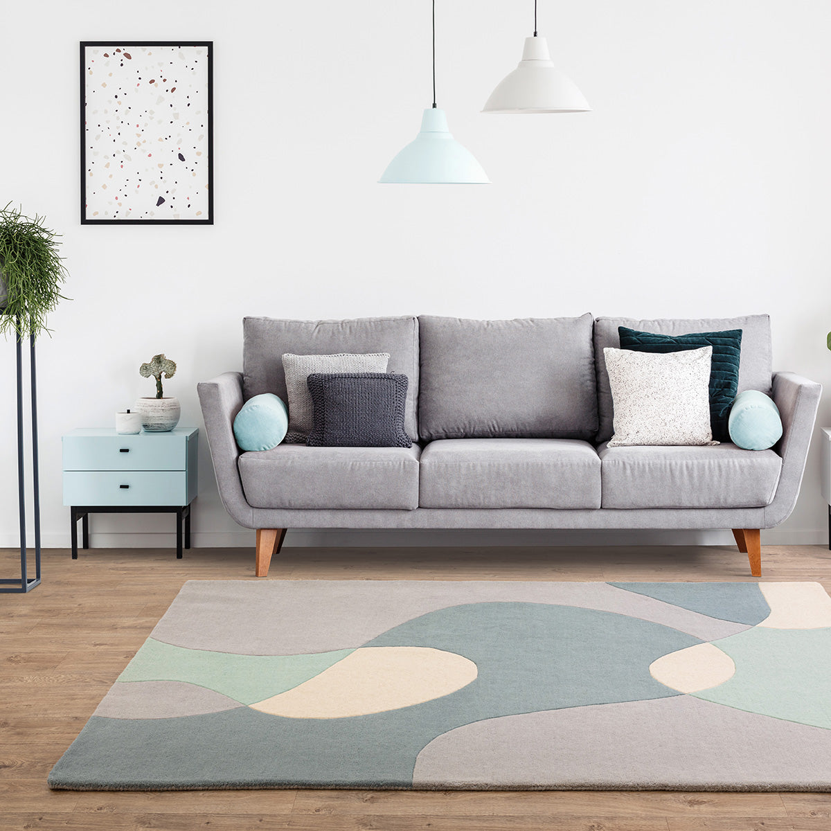 Gray sofa in a living room with a colorful rug and decorative pillows.