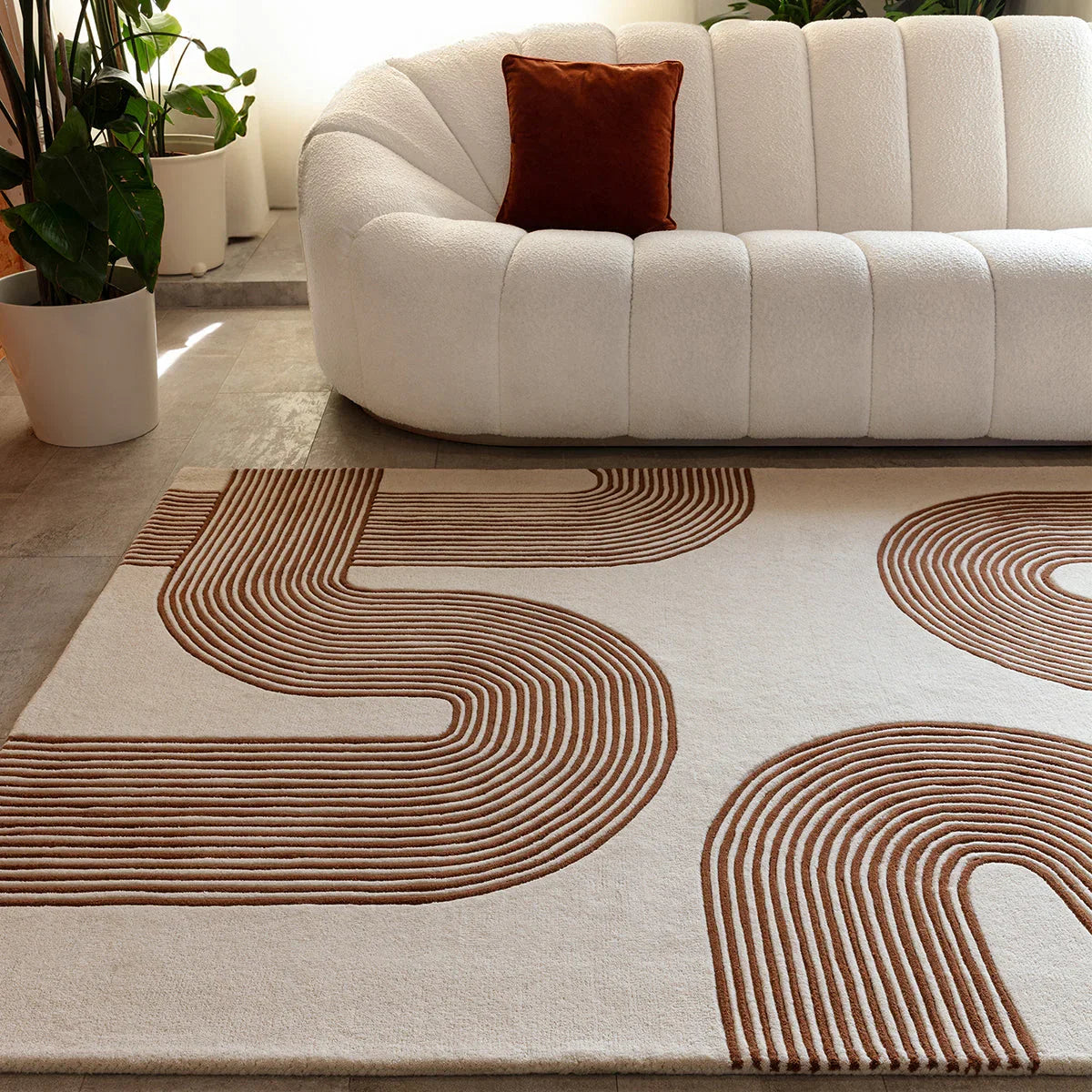 Beige and brown patterned rug in a living room with a white sofa and plants.