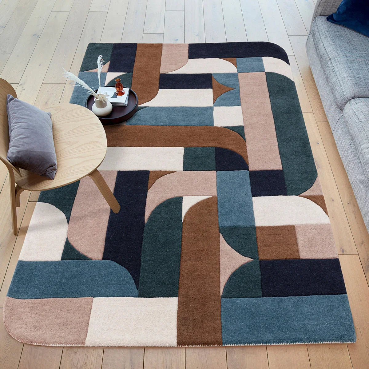 Geometric patterned rug on a wooden floor with a sofa and table in the background