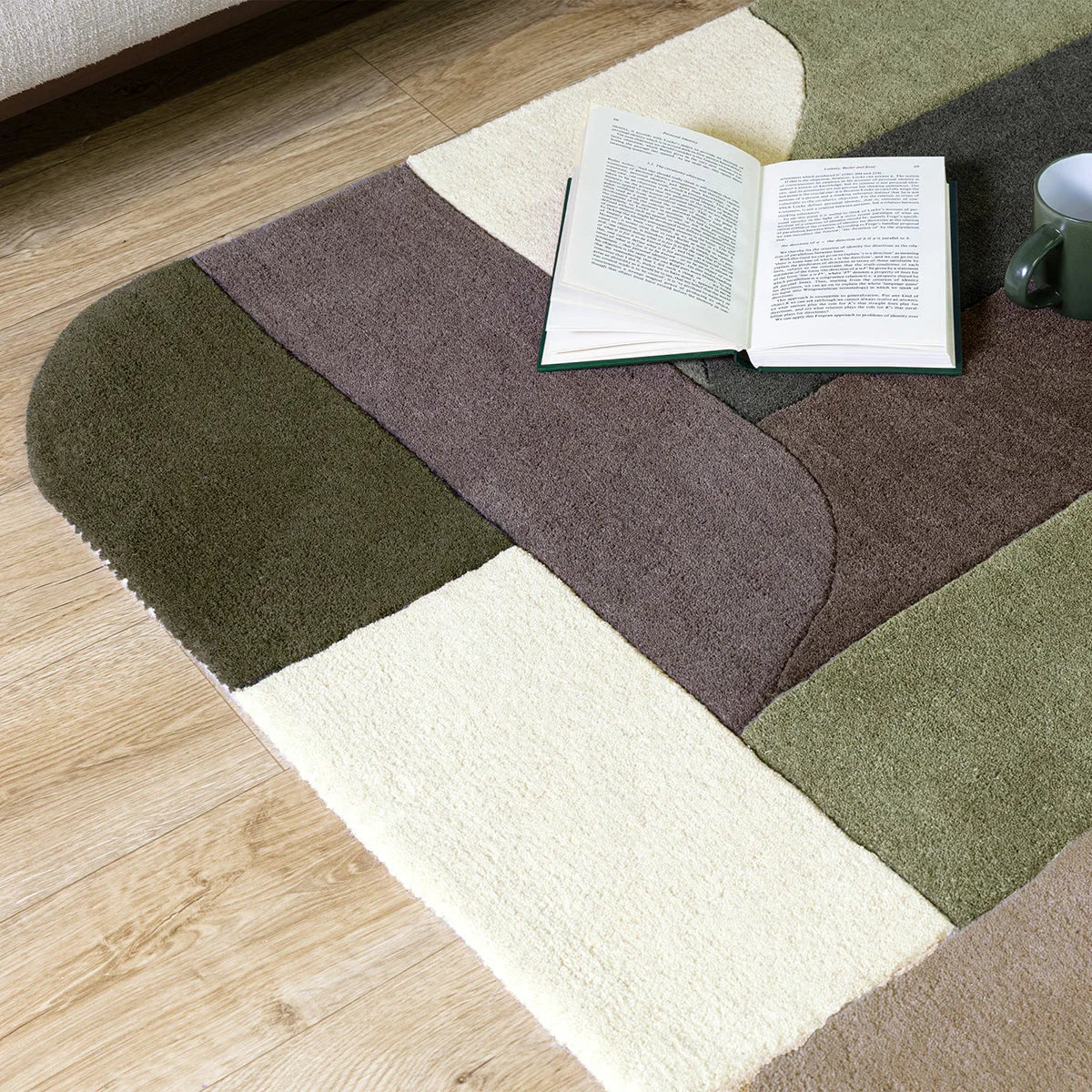 Asiatic Matrix 90 Klotski Sage Rug featuring geometric patchwork in sage, olive, brown, taupe and cream on natural wood floor, machine-made wool