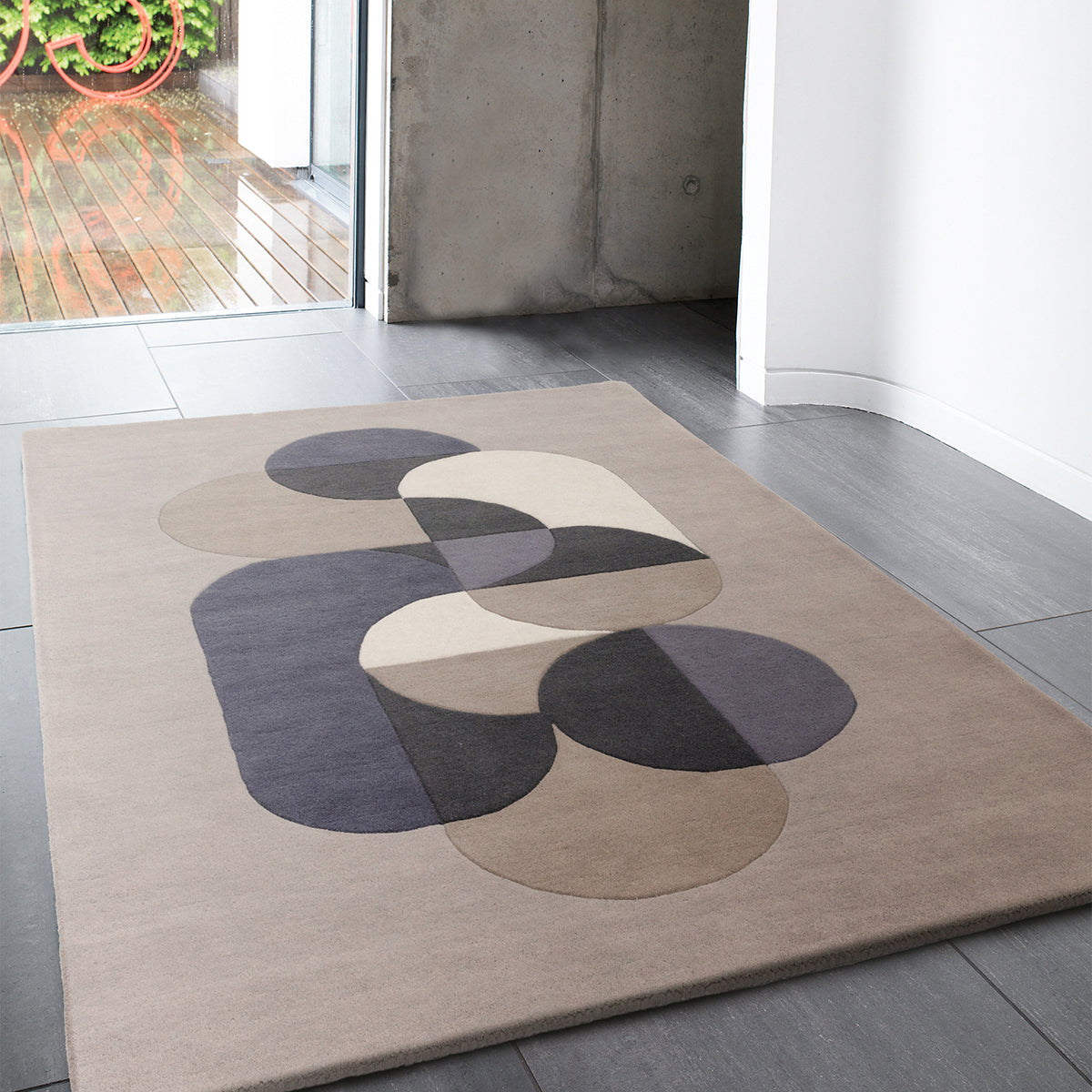 Beige rug with abstract black and gray shapes on a wooden floor.