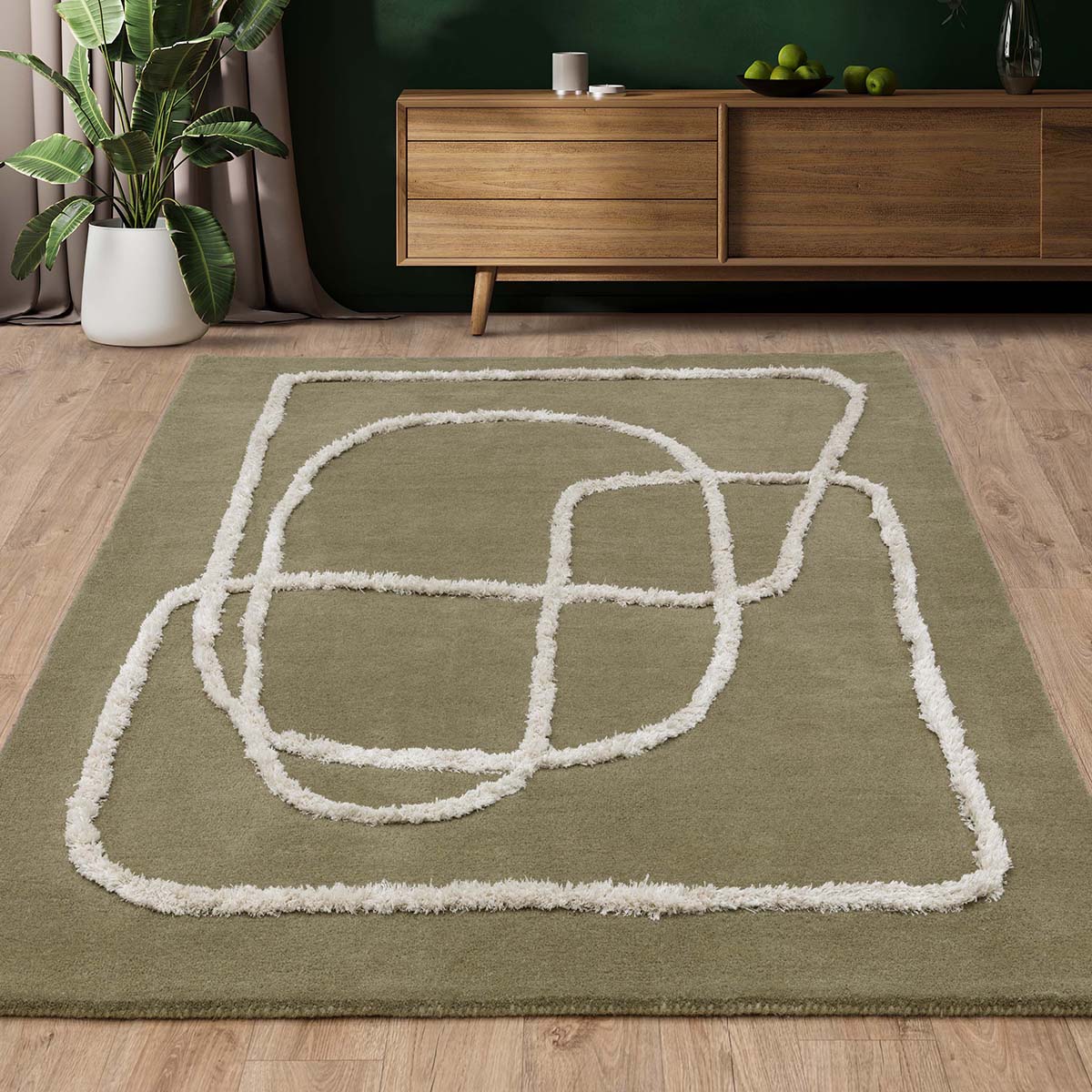 Green rug with white abstract design in a room with wooden furniture and plants.