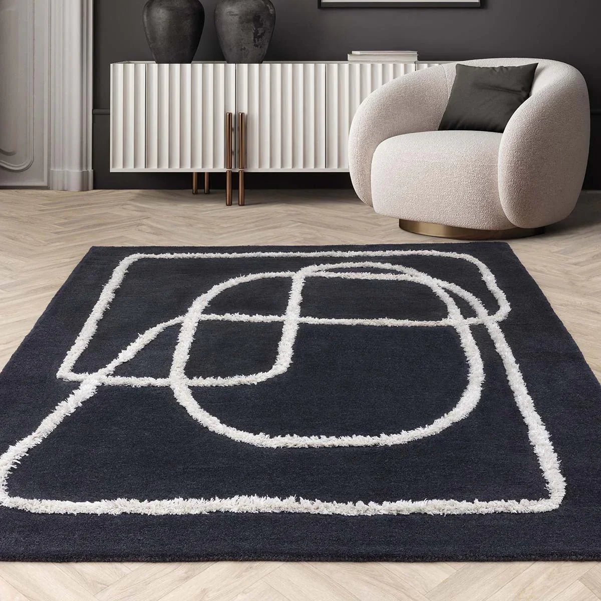 Modern room with a black rug featuring white geometric patterns, a beige armchair, and a white console table.