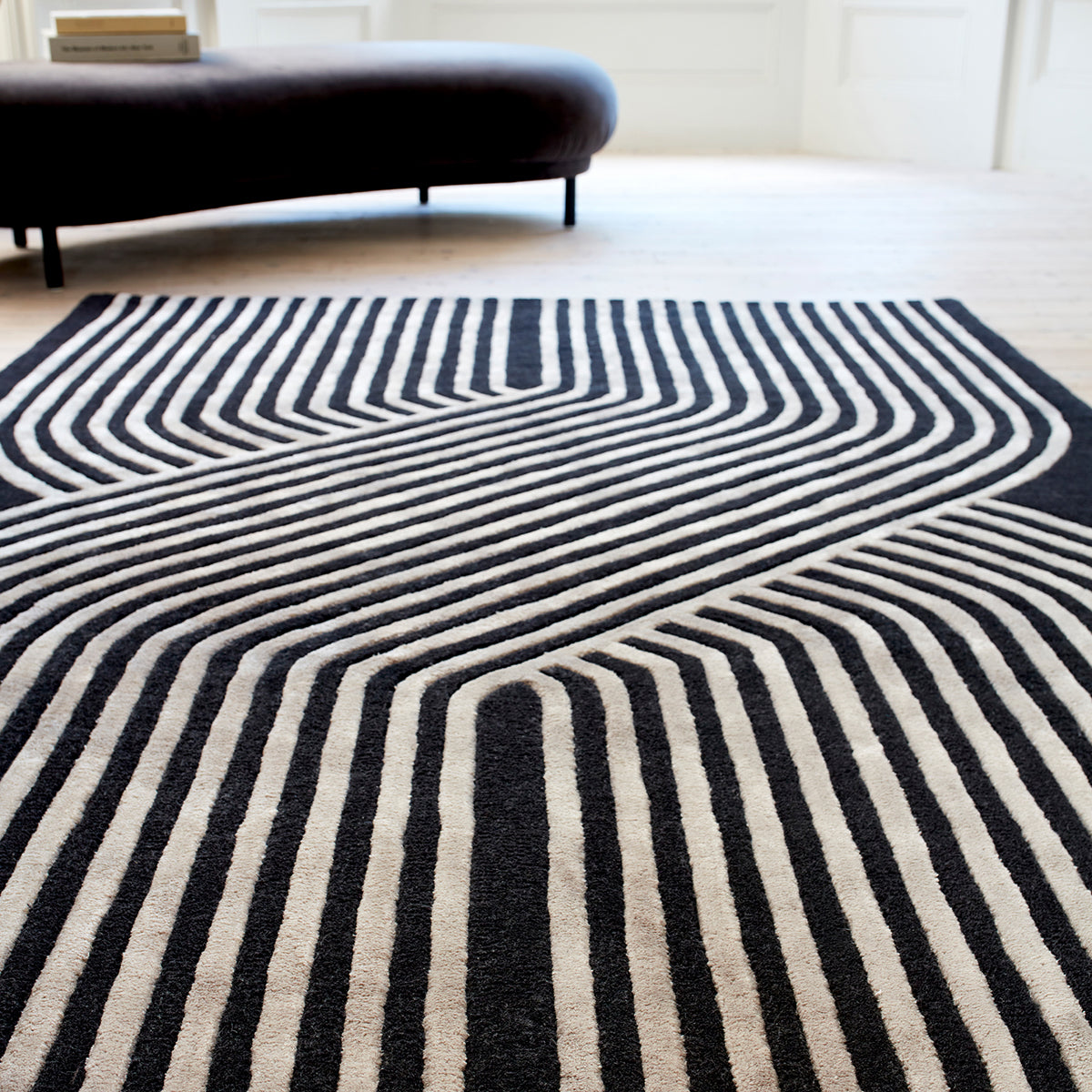 Black and white striped rug on a wooden floor with a modern sofa in the background.