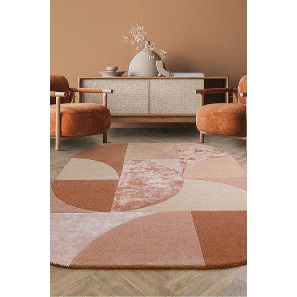 Asiatic Oval Earth Rug featuring geometric patchwork in dusty rose, terracotta, blush and cream on warm pink background, hand-tufted wool