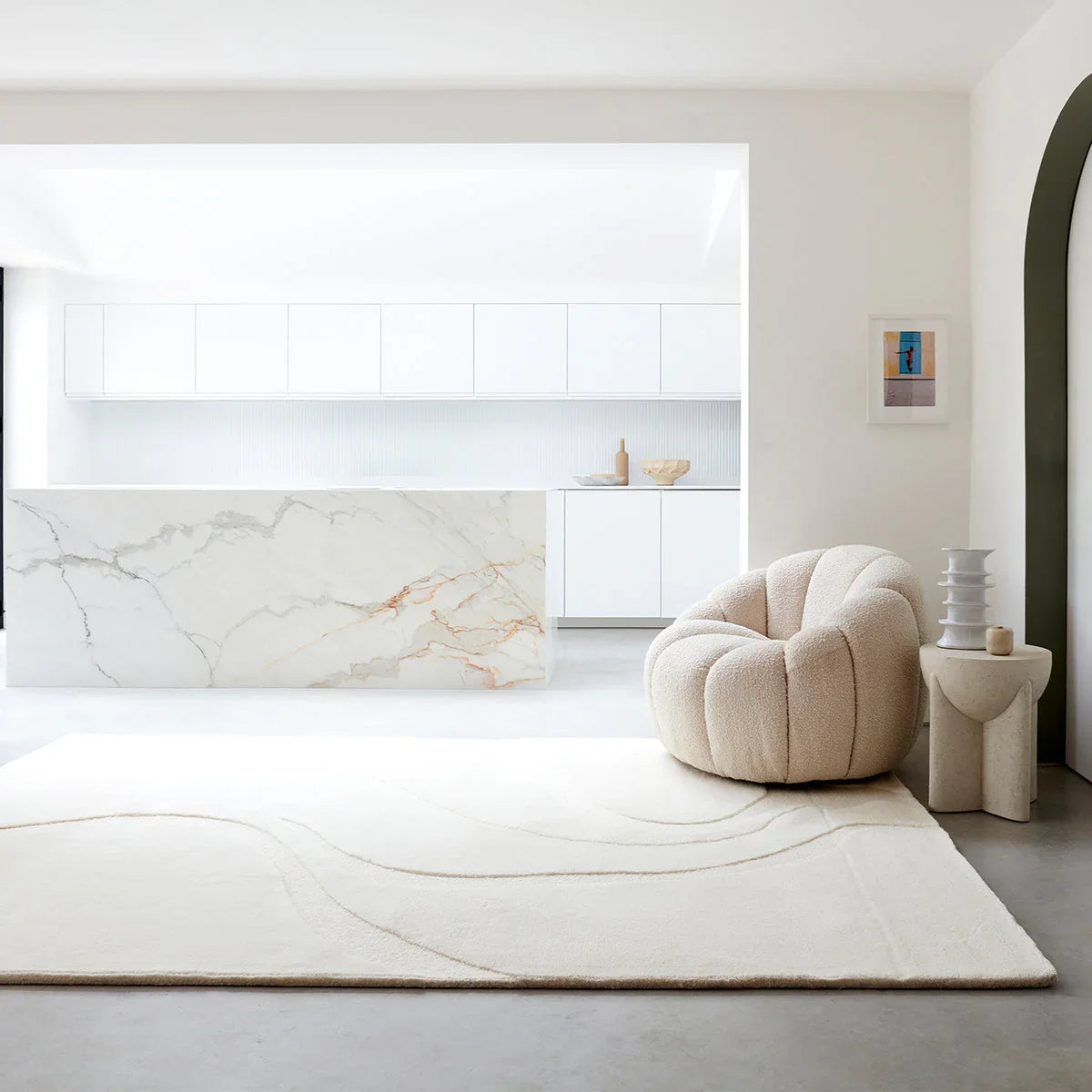 Modern living room with a beige armchair, white rug, and marble wall.