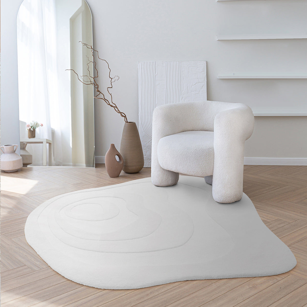 Modern white armchair on a white rug in a minimalistic room with light wood flooring.