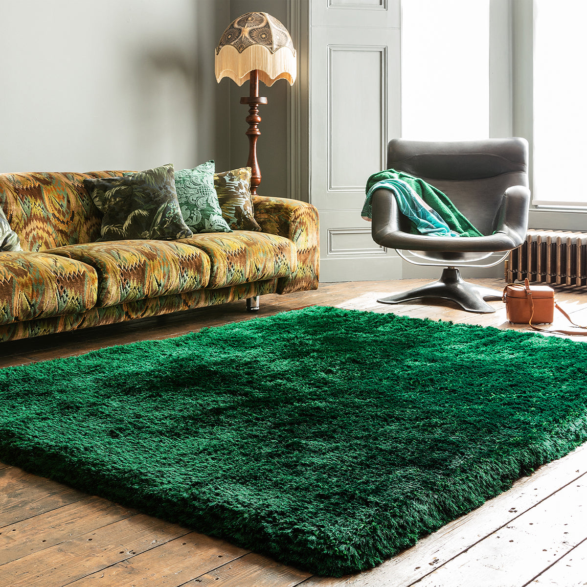 Living room with a green rug, patterned sofa, and armchair.
