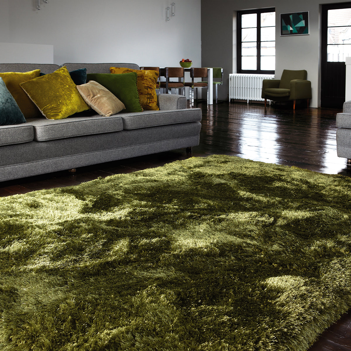 Living room with a green rug, gray sofa, and wooden floor.