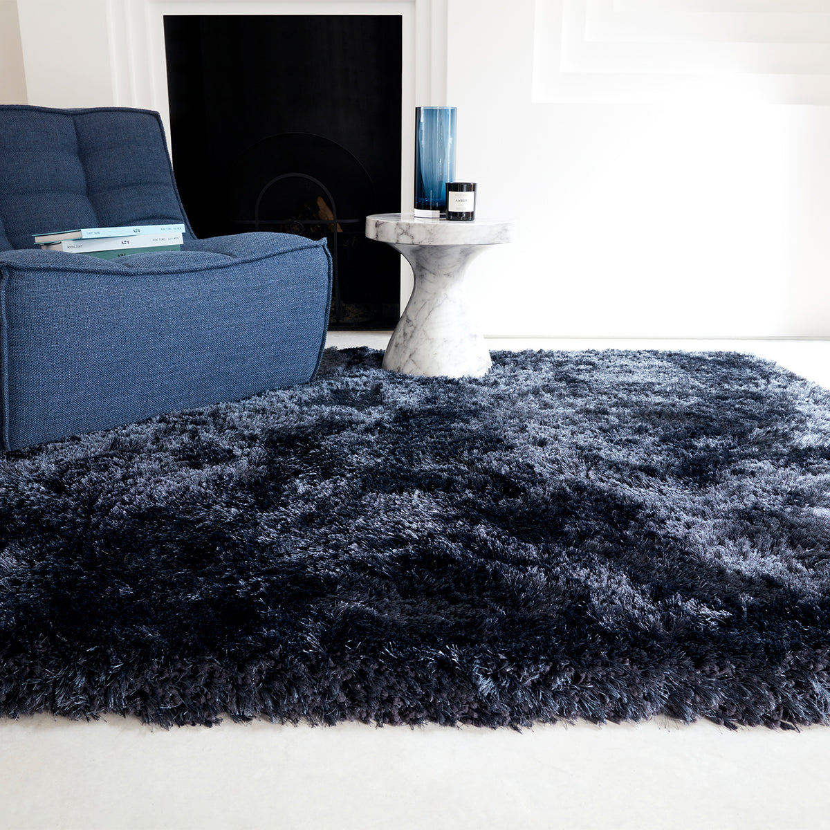 Blue shaggy rug in a living room setting with a blue sofa and a small table.