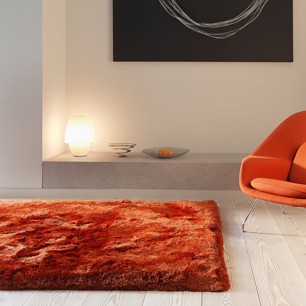 Modern living room with a red rug, orange chair, and abstract art on the wall.