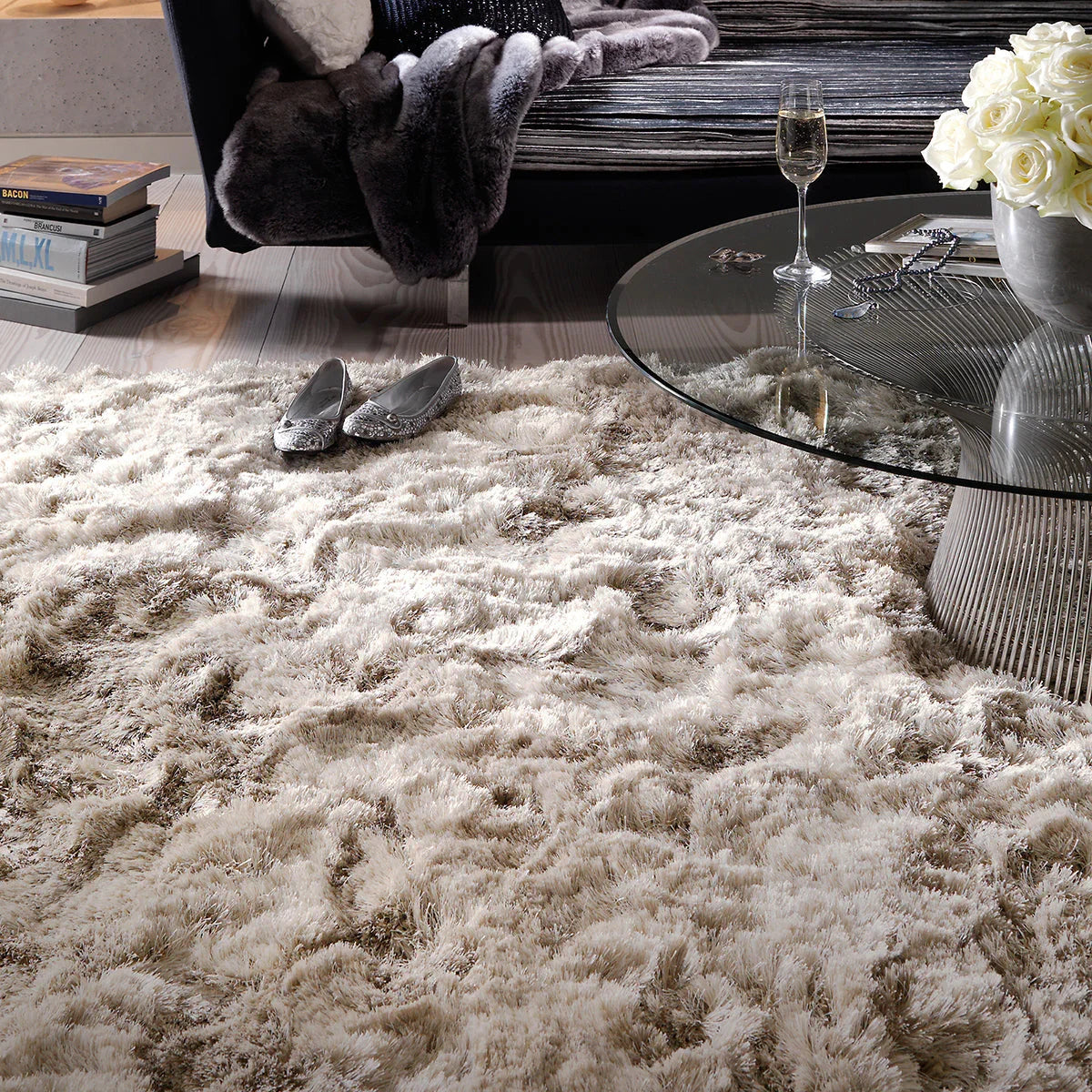Shaggy beige rug in a living room setting with a glass coffee table and decorative items.