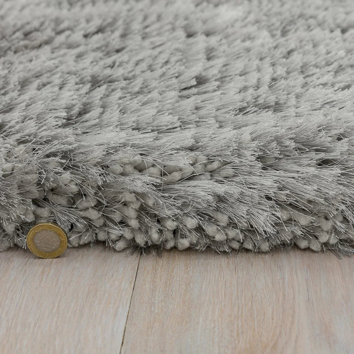 Asiatic Plush Silver Round Designer Rug featuring shag in silver and grey on pale wood floor, machine-made synthetic fibres