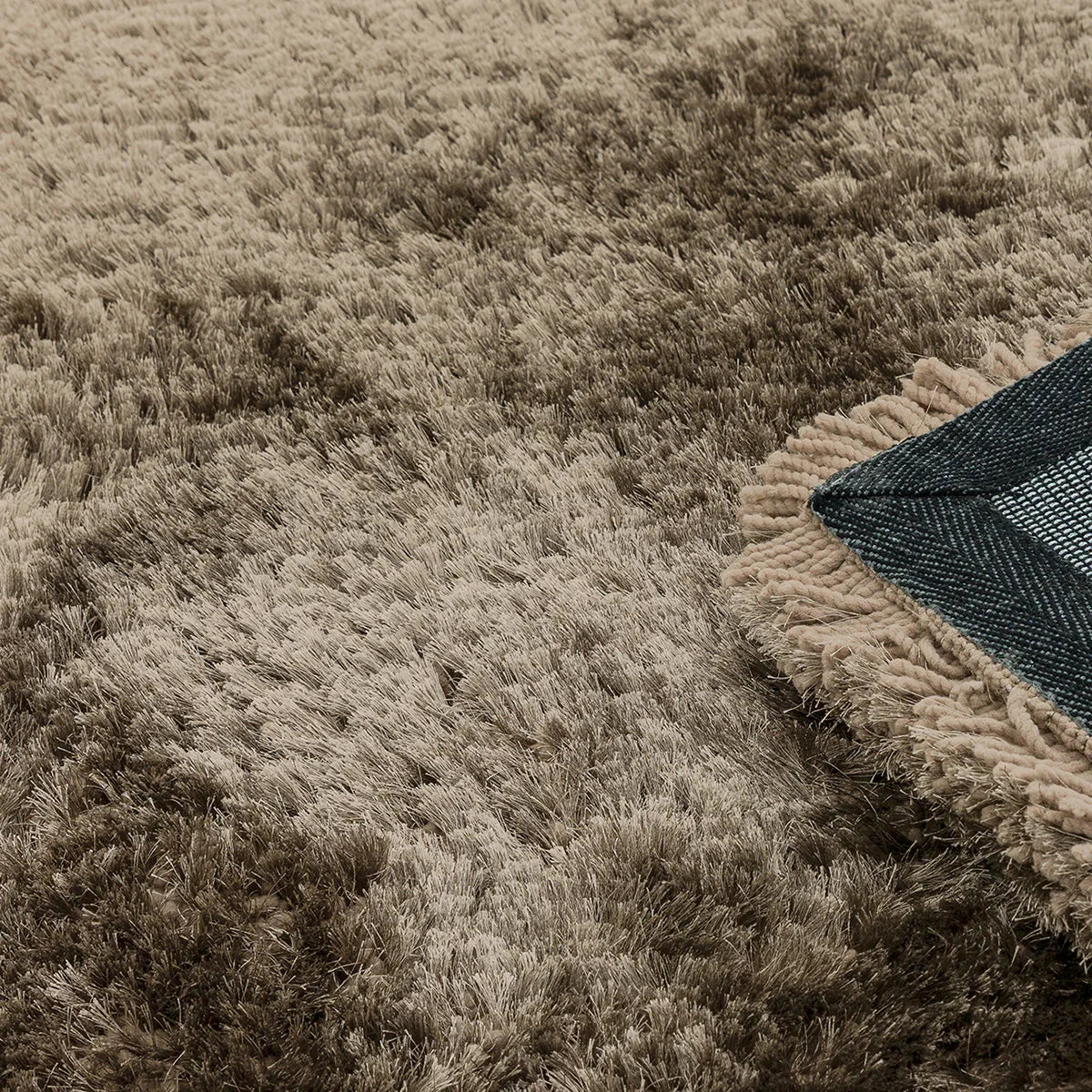 Asiatic Plush Taupe Round Rug featuring plush shag in taupe, cream and beige with navy underside, machine-made polyester