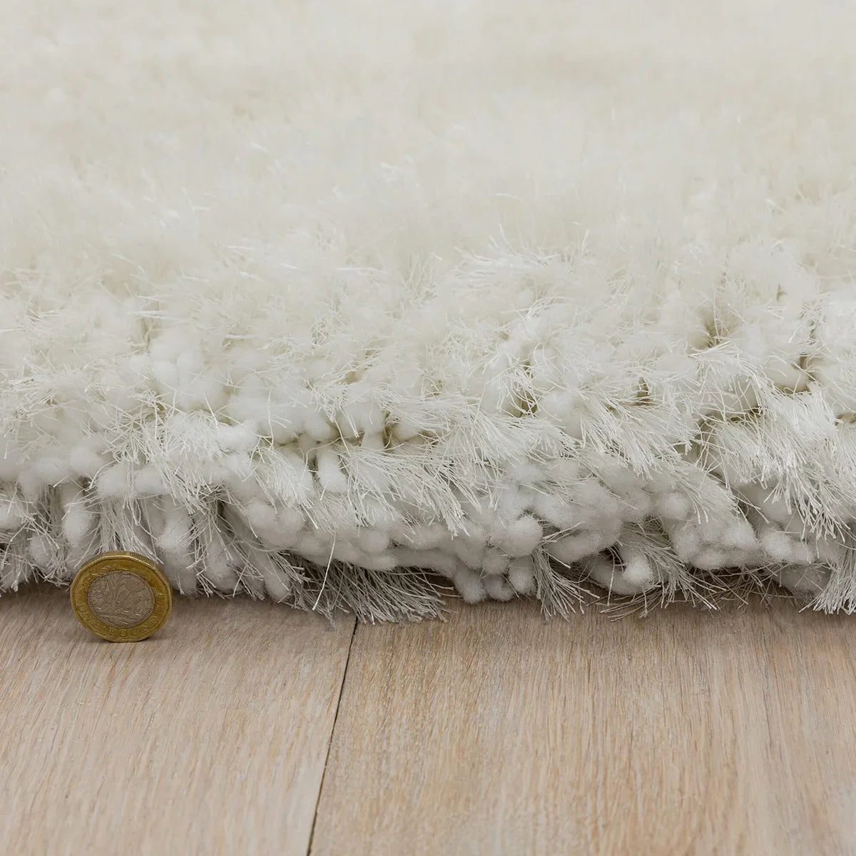 Asiatic Plush White Round Designer Rug featuring plush shag texture in white on light beige wood floor, machine-made synthetic fibers