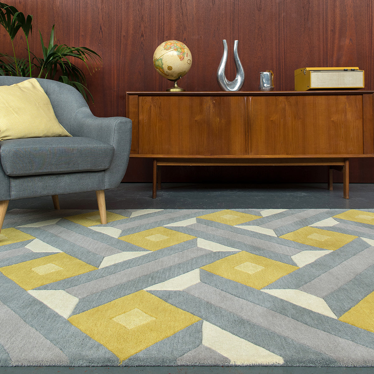 Living room with a geometric patterned rug, gray sofa, wooden sideboard, and decorative items.