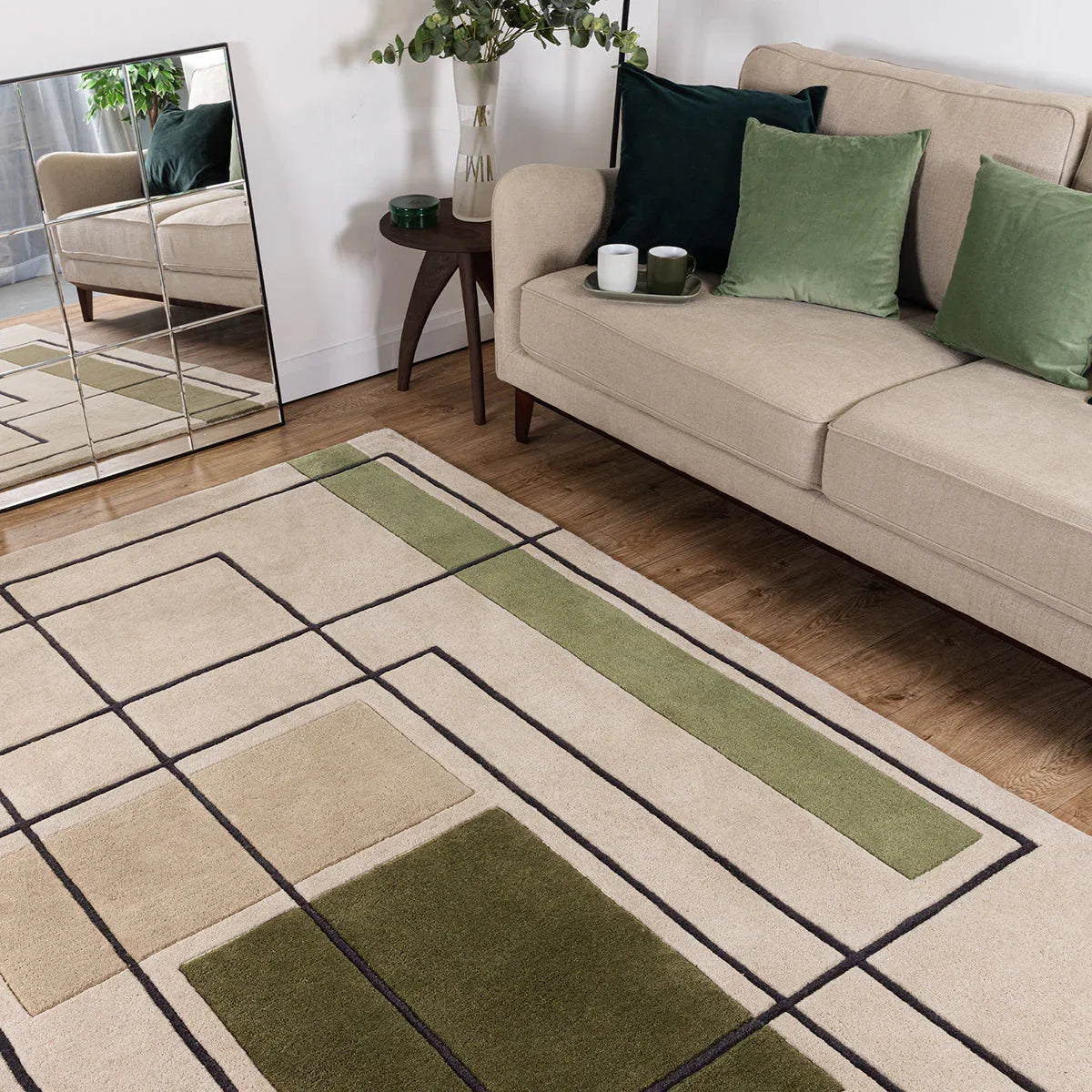 Beige and green area rug in a living room setting with a beige sofa and decorative pillows.