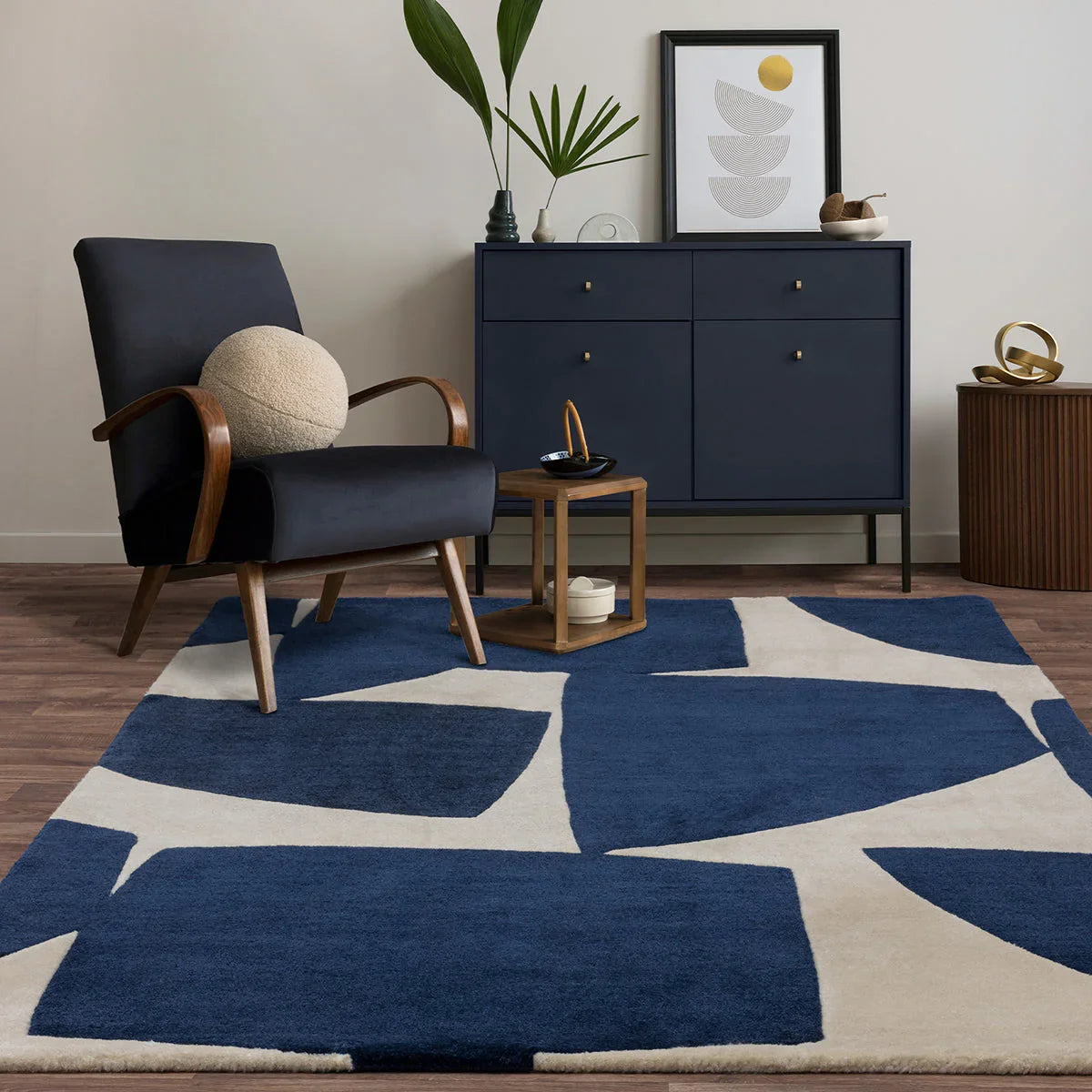 Modern room with a blue and white geometric rug, black armchair, and dark blue dresser.