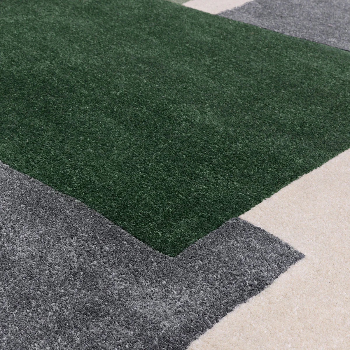 Asiatic Romy Papercut Green Designer Rug featuring geometric block pattern in dark green, charcoal grey and cream on beige background