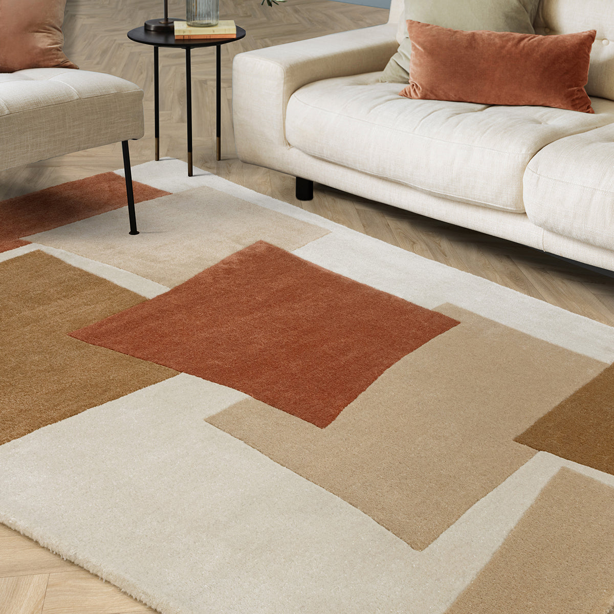 Geometric patterned rug on a wooden floor with a beige sofa and small table.